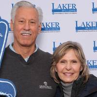 Two alumni posing together holding foam finger